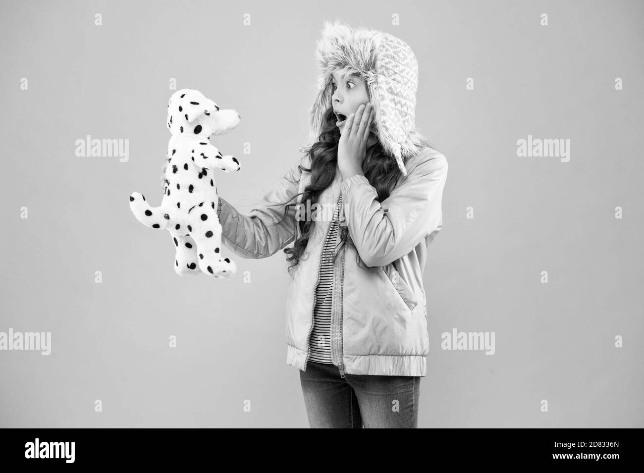 Incroyable. Happy kid demande communiquer chien. La charité et concept de don. Heureux petit enfant souriant jouer avec soft chien sur fond rose. Heureux petit enfant tenir jouer jouet. Concept de la bonté. Banque D'Images