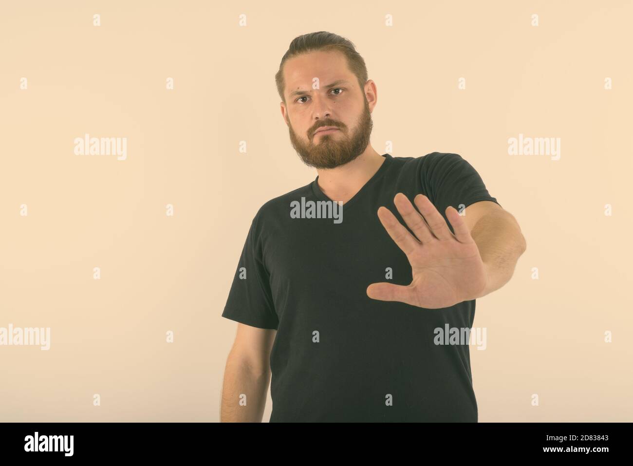 Portrait de jeune homme barbu montrant arrêter hand gesture against white background Banque D'Images