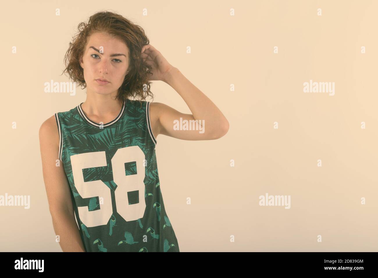 Portrait of teenage girl se coiffer contre fond blanc Banque D'Images