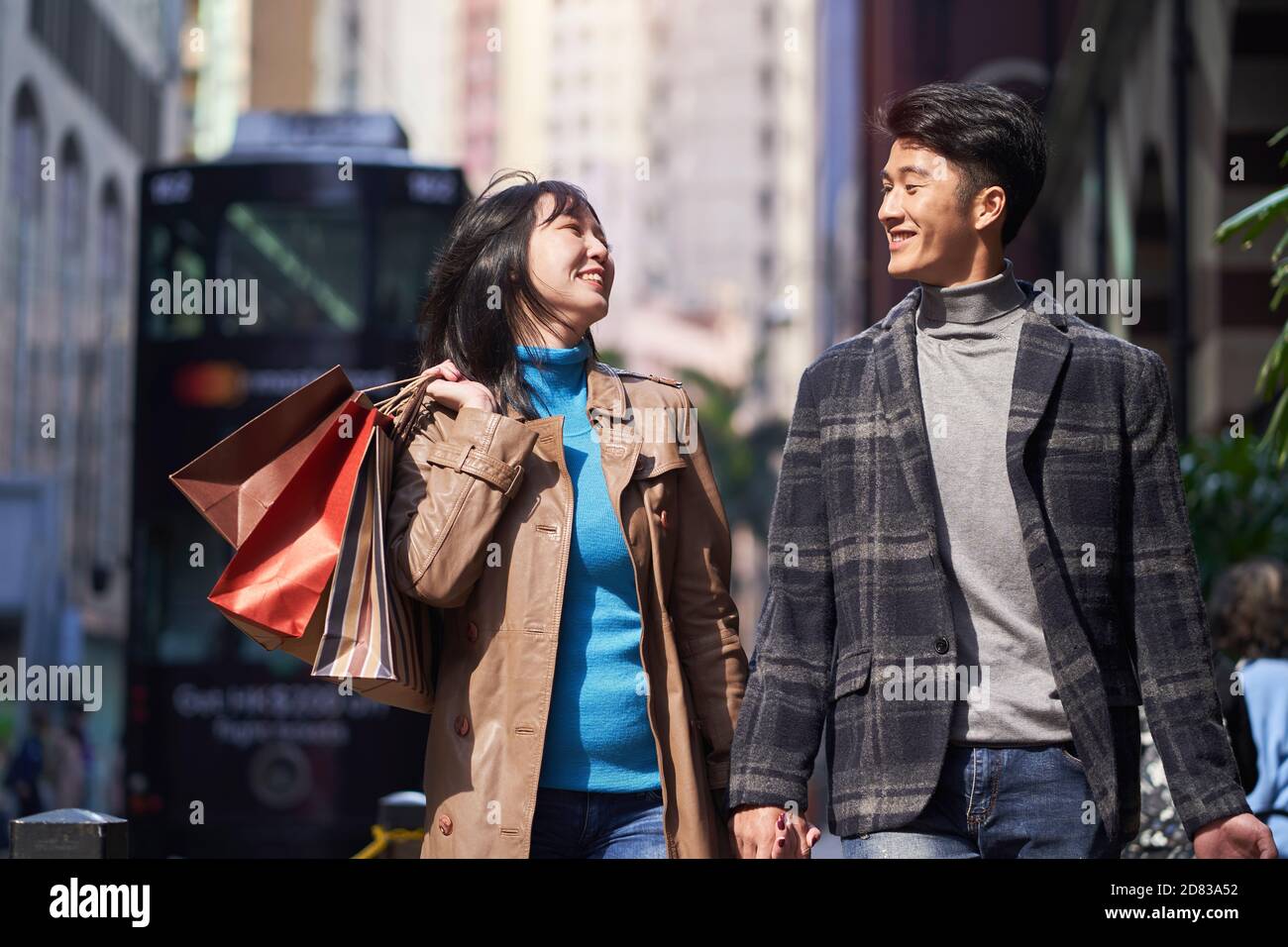 un jeune couple asiatique heureux et aimant qui marche dans la rue avec sacs à provisions à portée de main Banque D'Images