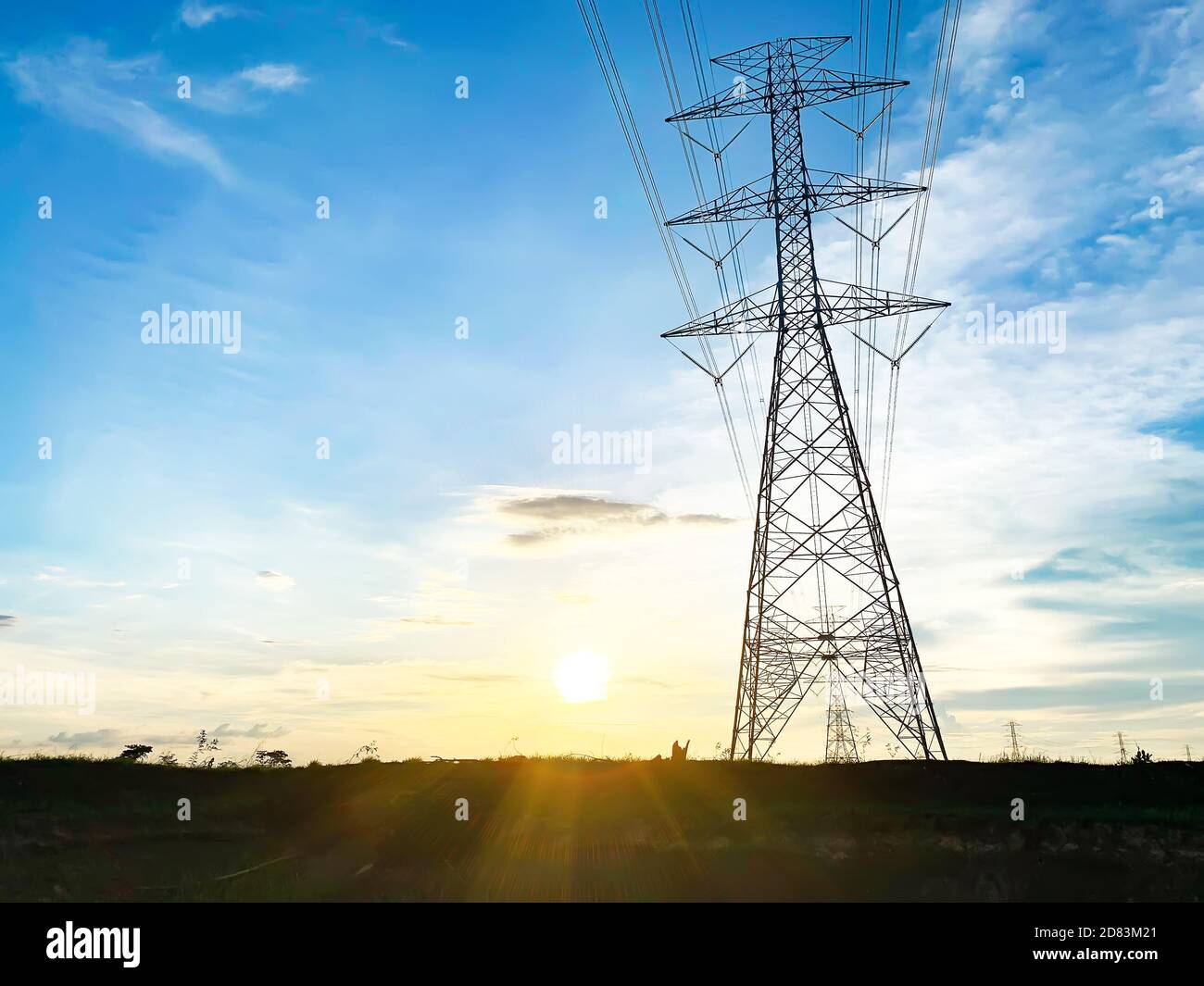 Un grand mât d'électricité haute tension installé sur le terrain avec un petit riz et le coucher du soleil dans la soirée. La structure en acier pour la base de la haute volta Banque D'Images