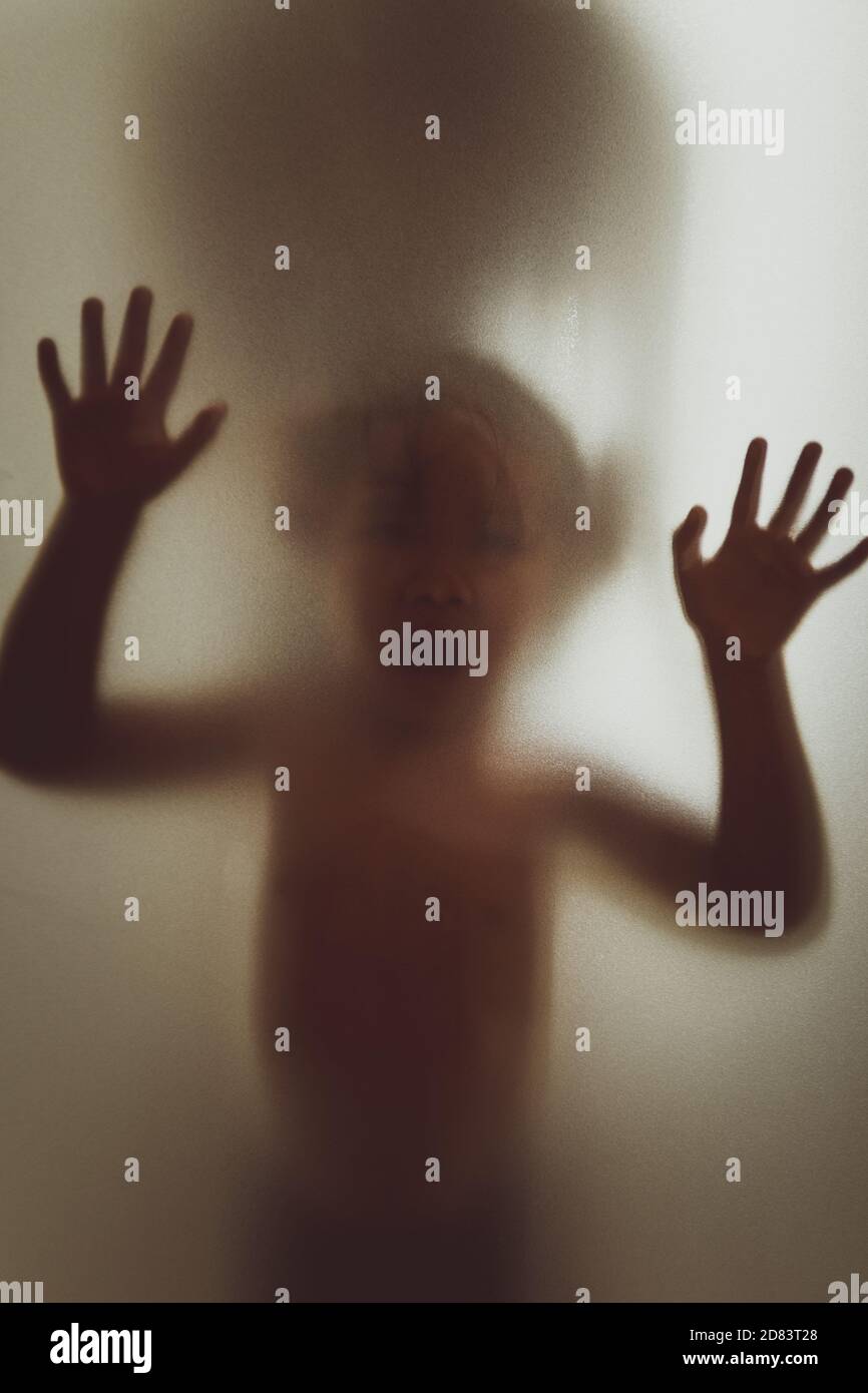 Fantôme concept ombre d'un enfant derrière le verre mat mise au point flou pour les mains et le corps Banque D'Images