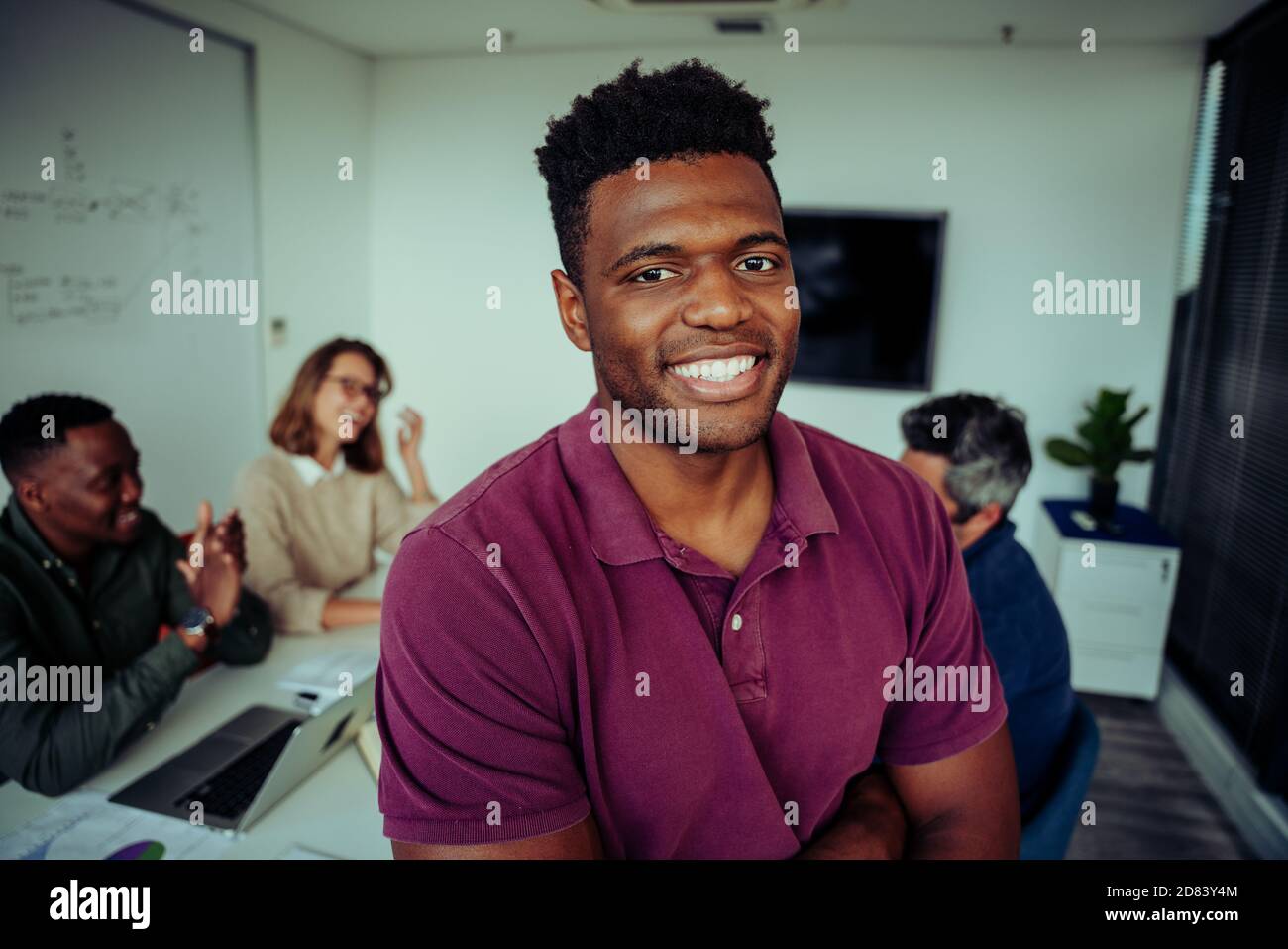 Portrait d'un jeune homme de race mixte souriant avec assurance avant la présentation devant les collègues dans la salle du conseil Banque D'Images