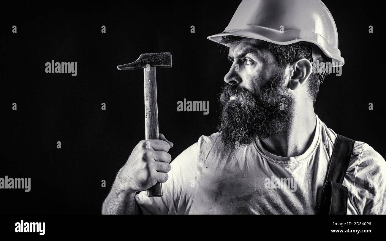 Homme barbu travailleur avec barbe, casque de construction, casque de sécurité. Constructeur en casque, marteau, handyman, constructeurs en casque. Marteler au marteau. Noir et blanc Banque D'Images