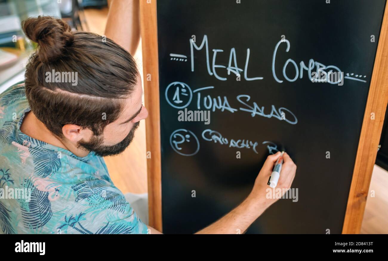 Gros plan du jeune serveur qui écrit le menu du jour Banque D'Images