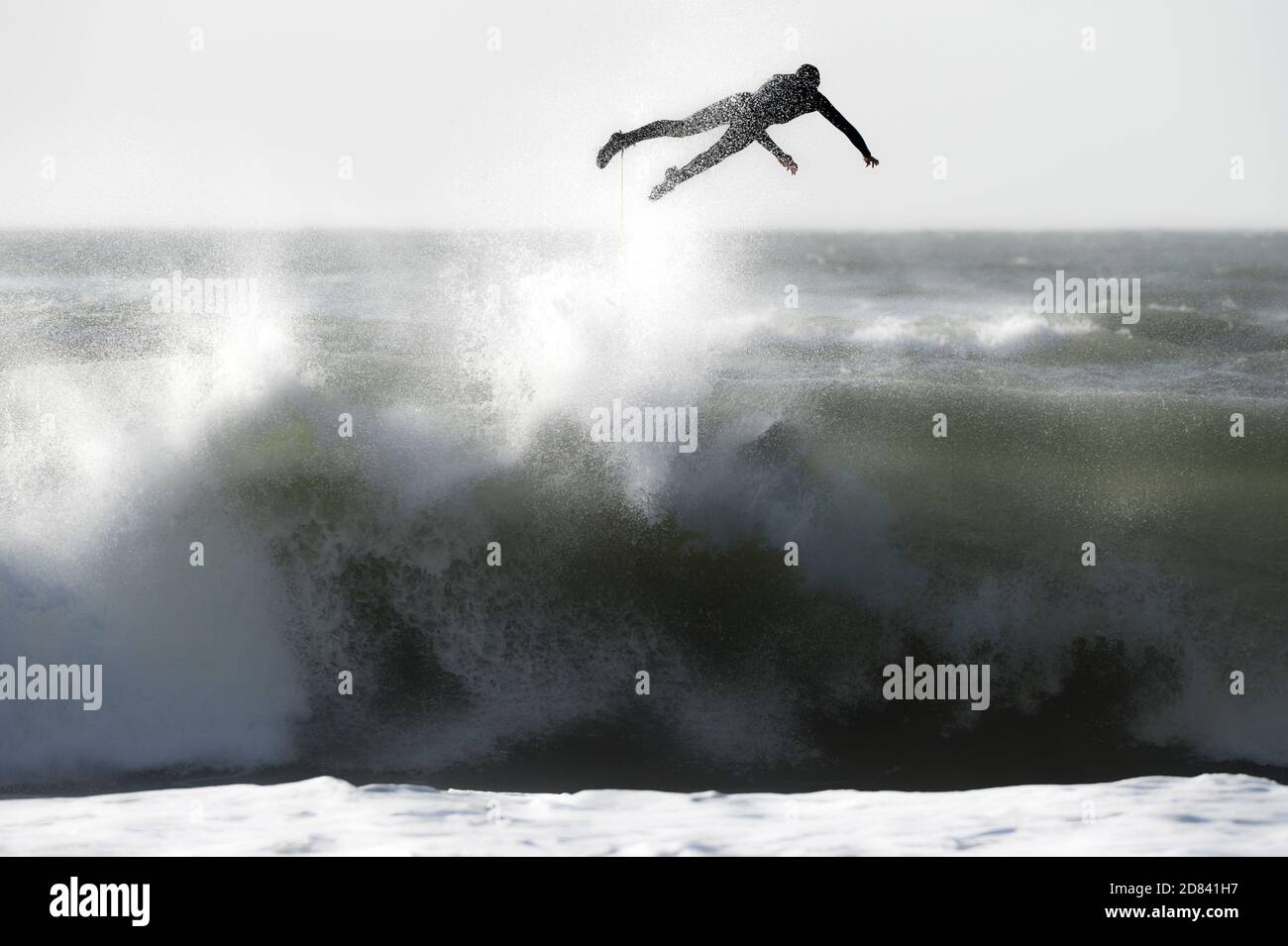Surfeur vole à l'arrière de la grande vague à Langland Bay dans le surf d'orage tandis que son conseil, attaché par la laisse est aspiré au-dessus des chutes - essuyeur classique. Banque D'Images