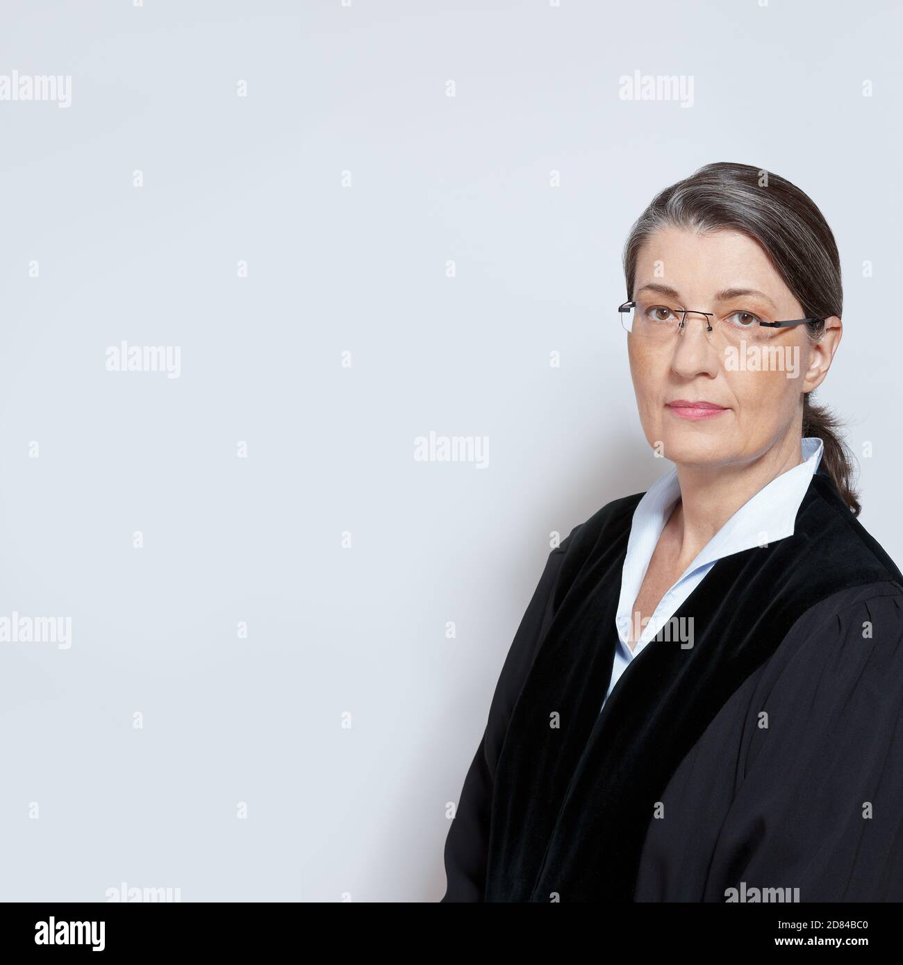 Portrrait d'une femme d'âge moyen juge en robe noire, fond neutre, copyspace. Banque D'Images