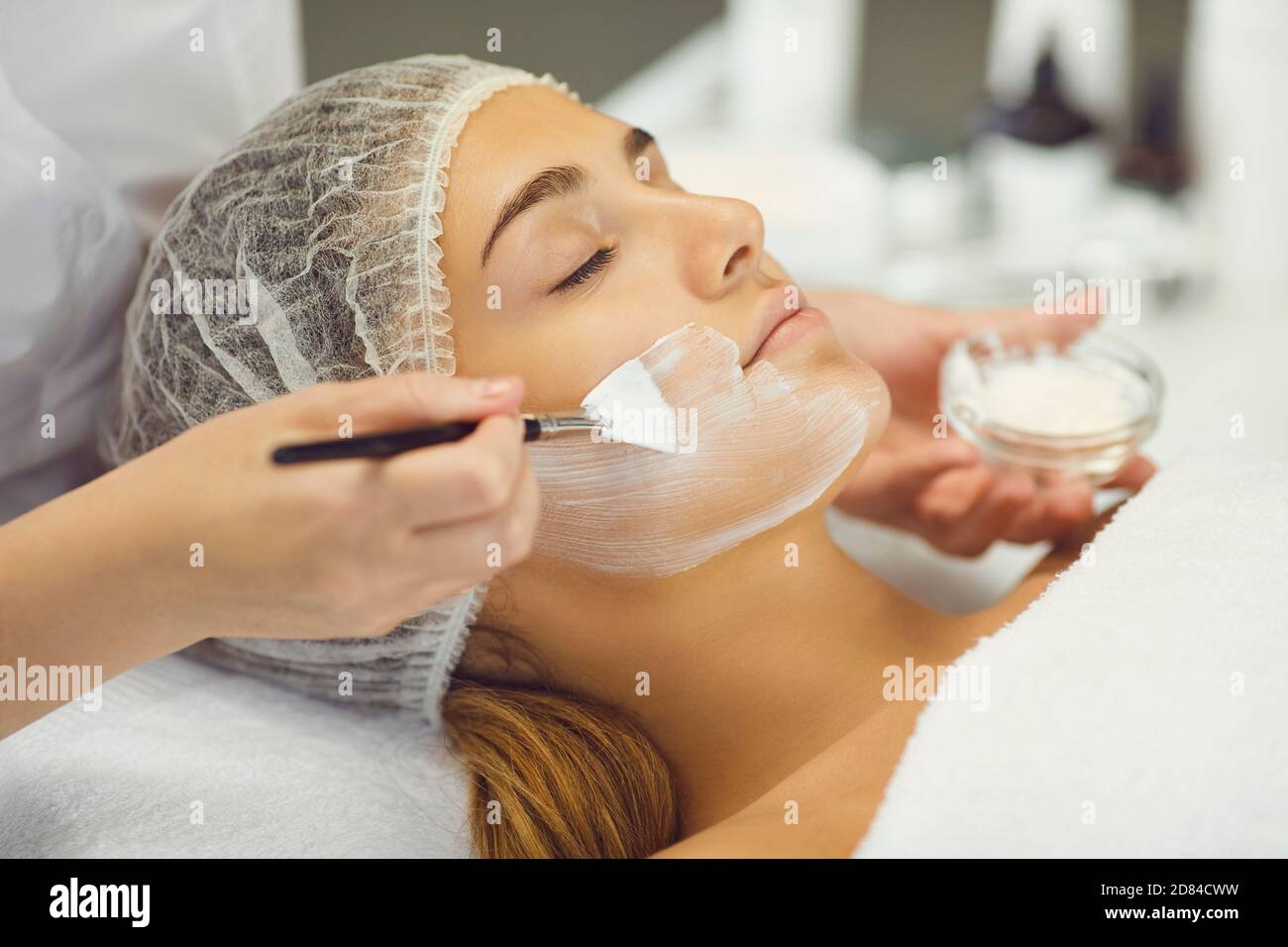 Jeune femme recevant la procédure d'application du masque hydratant en beauté salon Banque D'Images