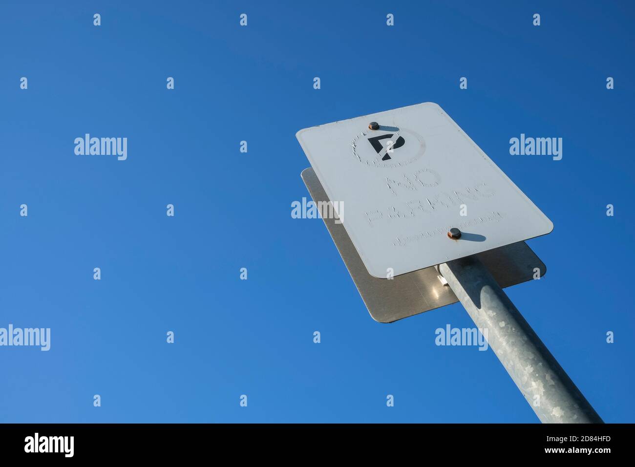 Endommagé par le soleil pas de signe de stationnement contre un ciel bleu clair. Banque D'Images