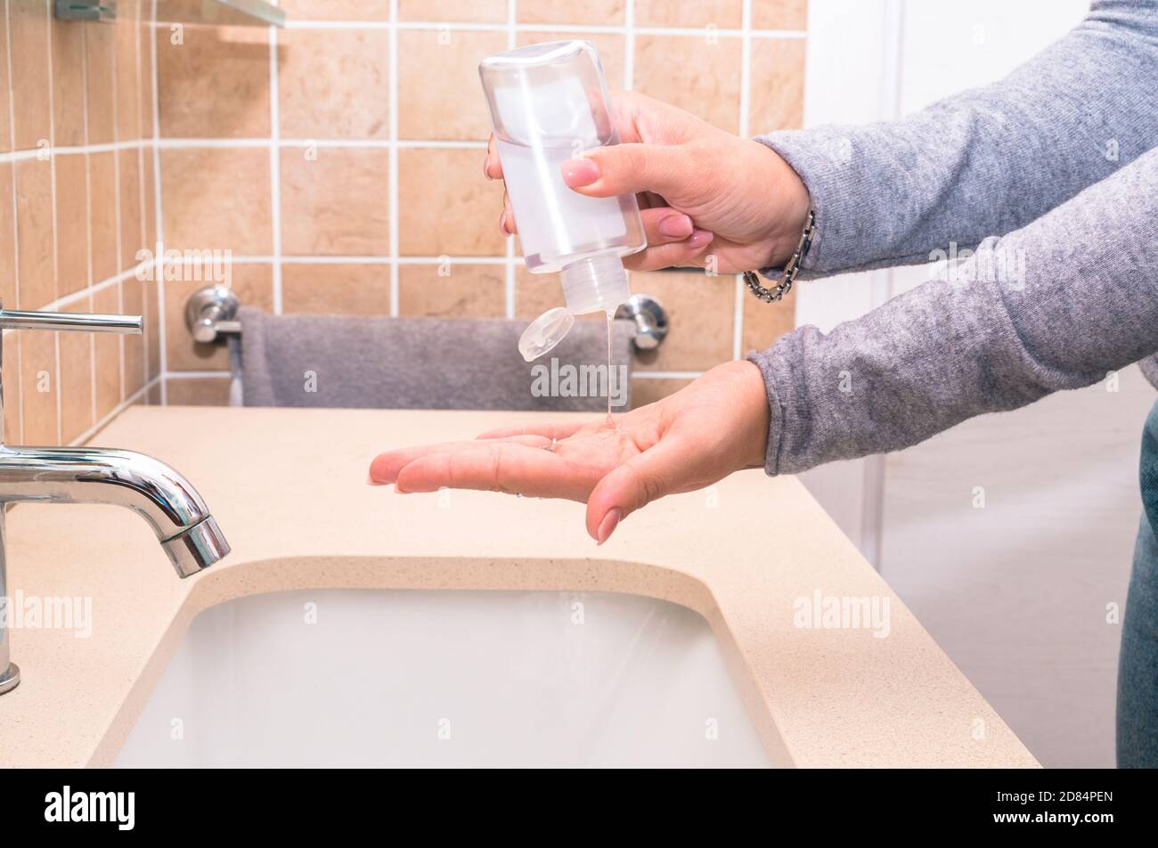 Covid-19 - femme nettoyant ses mains dans la salle de bains avec antibactérien Gel désinfectant - Nouveau concept normal de désinfection des mains Banque D'Images