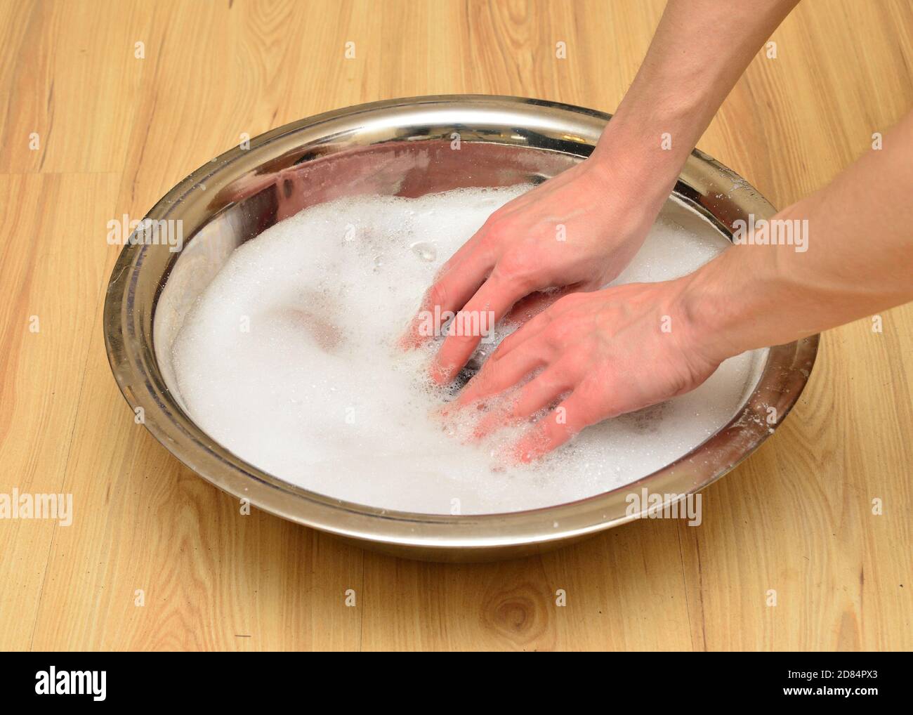 mains laver les vêtements dans un lavabo en métal avec de la mousse et du savon Banque D'Images