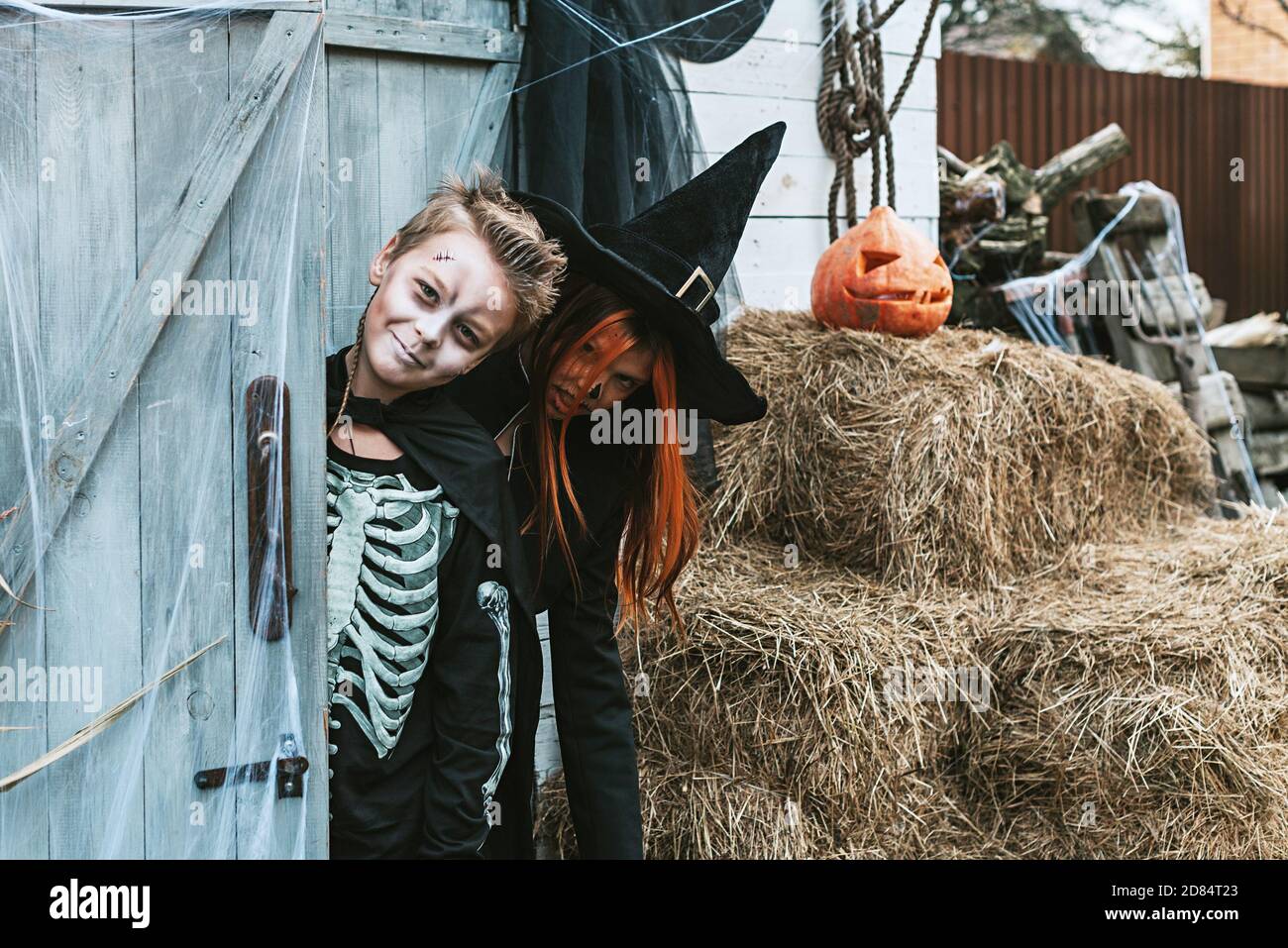 enfants un garçon dans un costume de squelette et une fille Dans un costume de sorcière s'amuser à une fête d'Halloween sur le porche décoré Banque D'Images