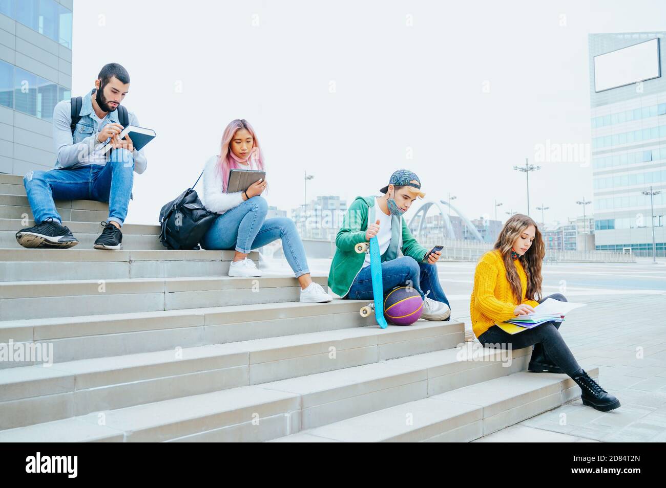 Groupe d'étudiants multiraciaux dans les masques protecteurs étudier assis sur Escaliers à distance sociale à l'extérieur d'un collège - amis heureux dans le temps du coronavirus mak Banque D'Images