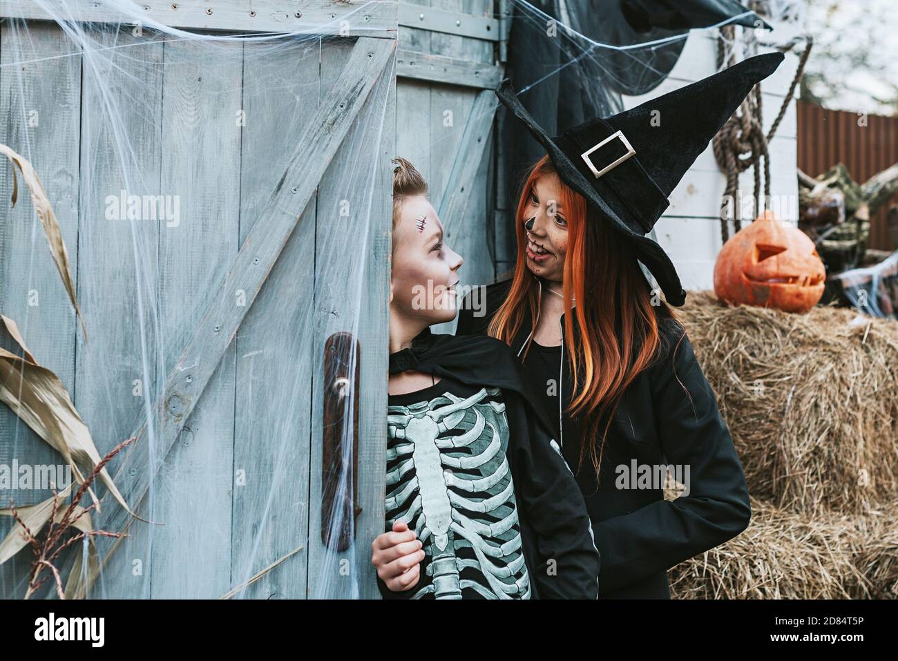 enfants un garçon dans un costume de squelette et une fille Dans un costume de sorcière s'amuser à une fête d'Halloween sur le porche décoré Banque D'Images