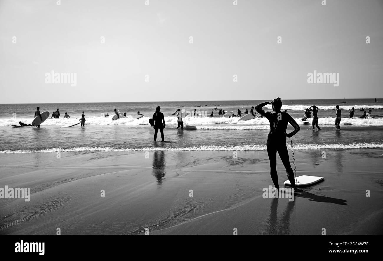 Image monochrome de Surfers jouer au bord de la plage en noir et blanc dans les combinaisons à Croyde Bay, Devon Banque D'Images