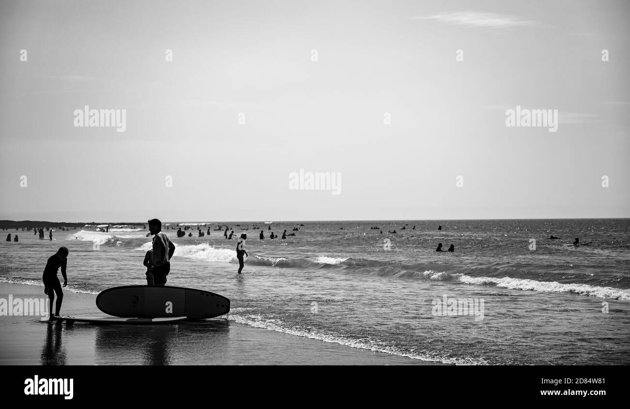 Image monochrome de Surfers jouer au bord de la plage en noir et blanc dans les combinaisons à Croyde Bay, Devon Banque D'Images