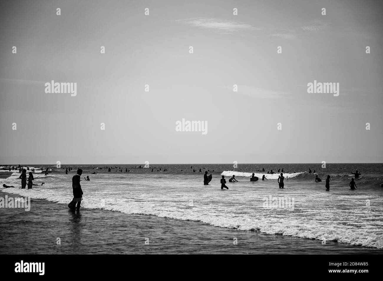 Image monochrome de Surfers jouer au bord de la plage en noir et blanc dans les combinaisons à Croyde Bay, Devon Banque D'Images