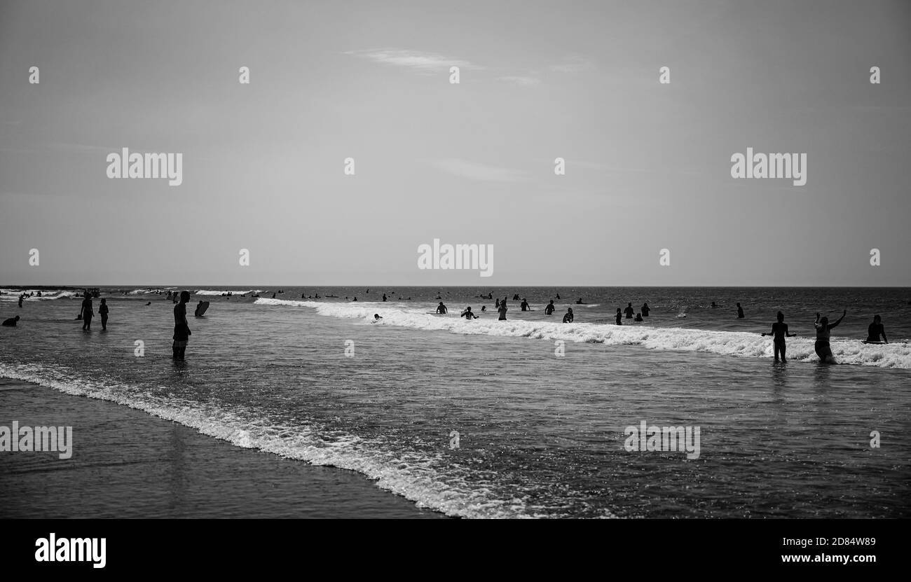 Image monochrome de Surfers jouer au bord de la plage en noir et blanc dans les combinaisons à Croyde Bay, Devon Banque D'Images