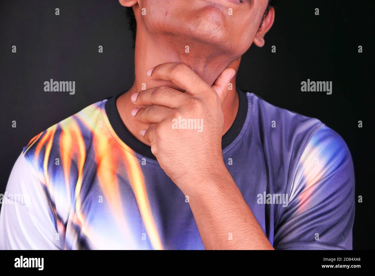 Jeune homme avec mal de gorge sur fond noir Banque D'Images
