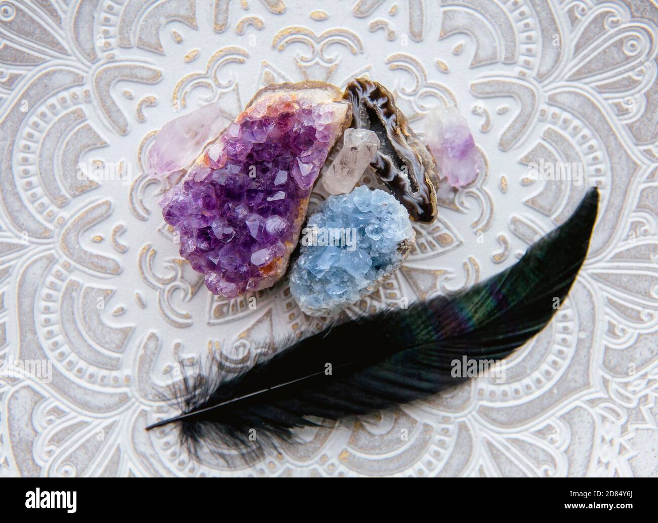 Vue plate de plusieurs géodes de cristal améthyste, celestite. Avec plume d'oiseau brillante noire. Banque D'Images