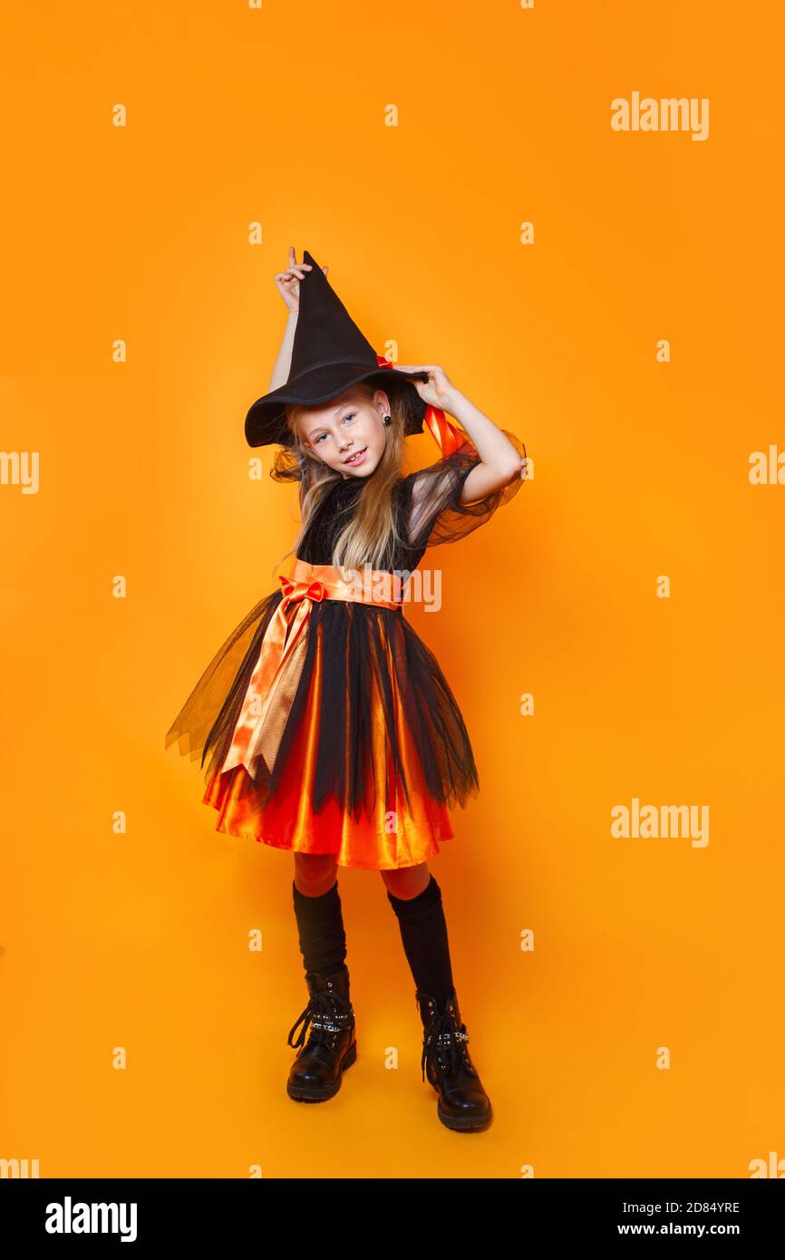 Drôle petite fille dans sorcière Halloween costume sur fond orange Banque D'Images