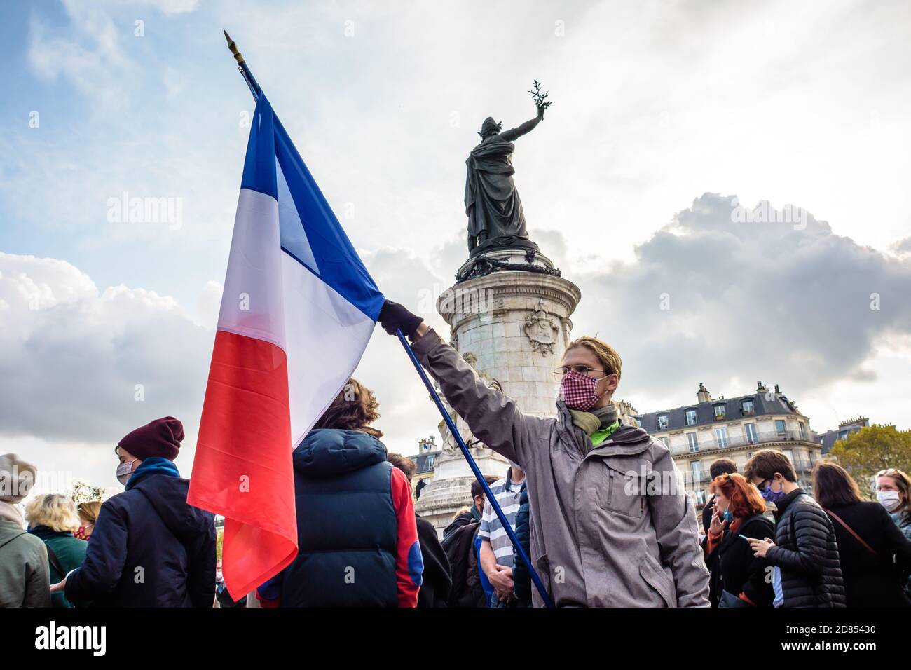 Un homme portant un masque facial porte un drapeau français au pied du Monument à la République lors d'une manifestation à Paris, en France. Banque D'Images
