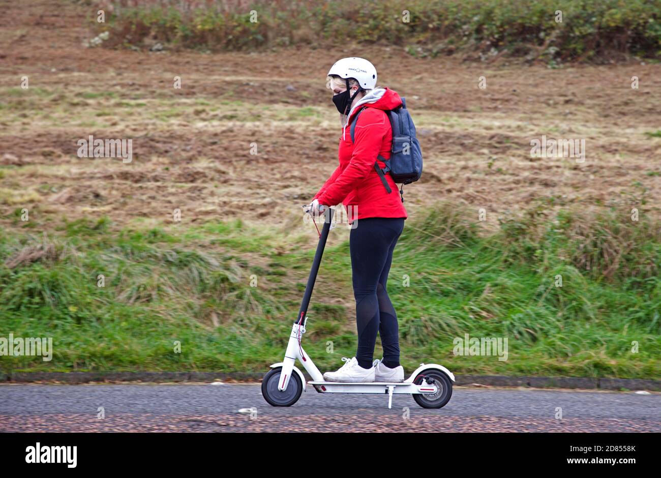 Holyrood Park, Édimbourg, Écosse, Royaume-Uni. 27 octobre 2020. Température de 8 degrés centigrade et ciel gris plomb avant de fortes pluies plus tard au parc dans le centre-ville. Photo : femme sur scooter électrique sur la route. Au cours de la semaine dernière, la police d'Édimbourg a arrêté quelques pilotes d'autocuiseurs électriques qui ont ensuite été inculpés parce que les scotters sont illégaux pour être utilisés sur les routes et les trottoirs publics, à moins d'être embauchés par une compagnie qui fournit la bonne assurance. Banque D'Images