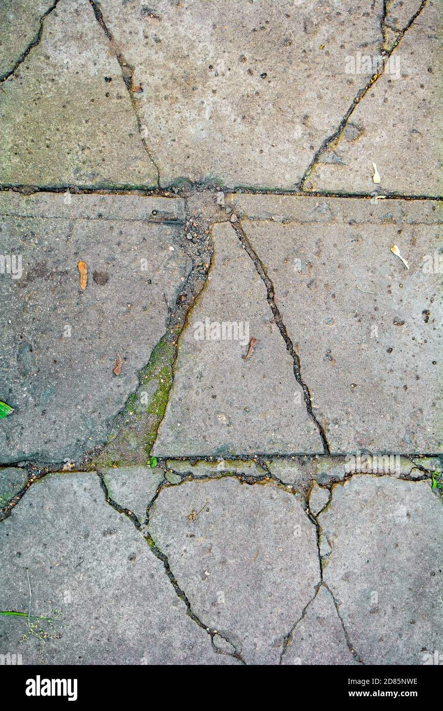 Vue de dessus abstraite craquelée béton brique chemin texture. Carreaux de trottoir cassés gros plan, à travers ses fissures et fissures herbe se brise à travers Banque D'Images