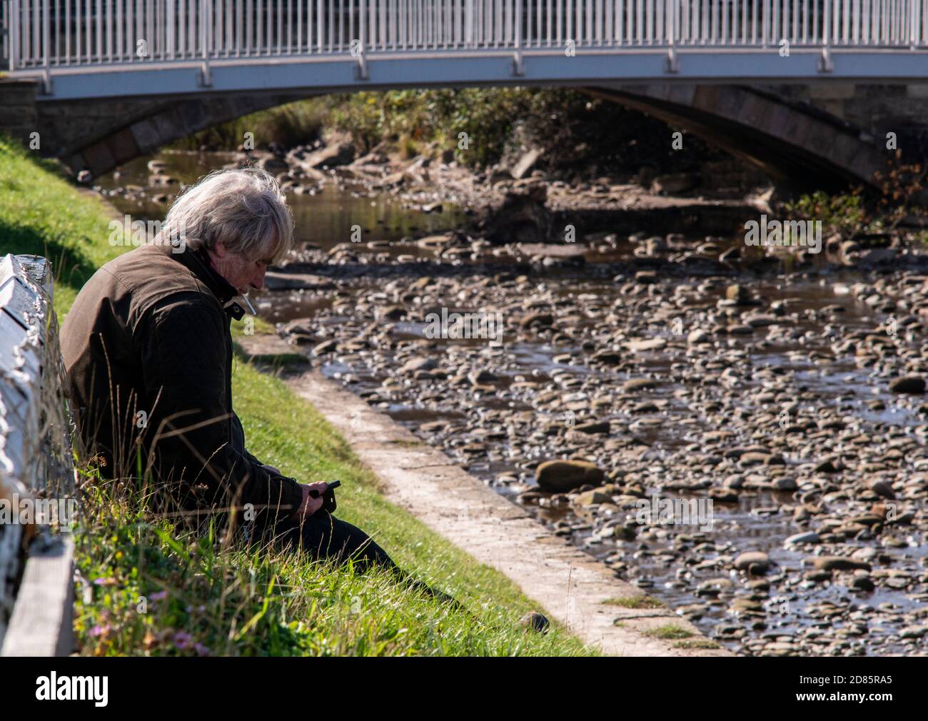 Homme assis sur la rive fumeur, Whitby, Angleterre, Royaume-Uni Banque D'Images