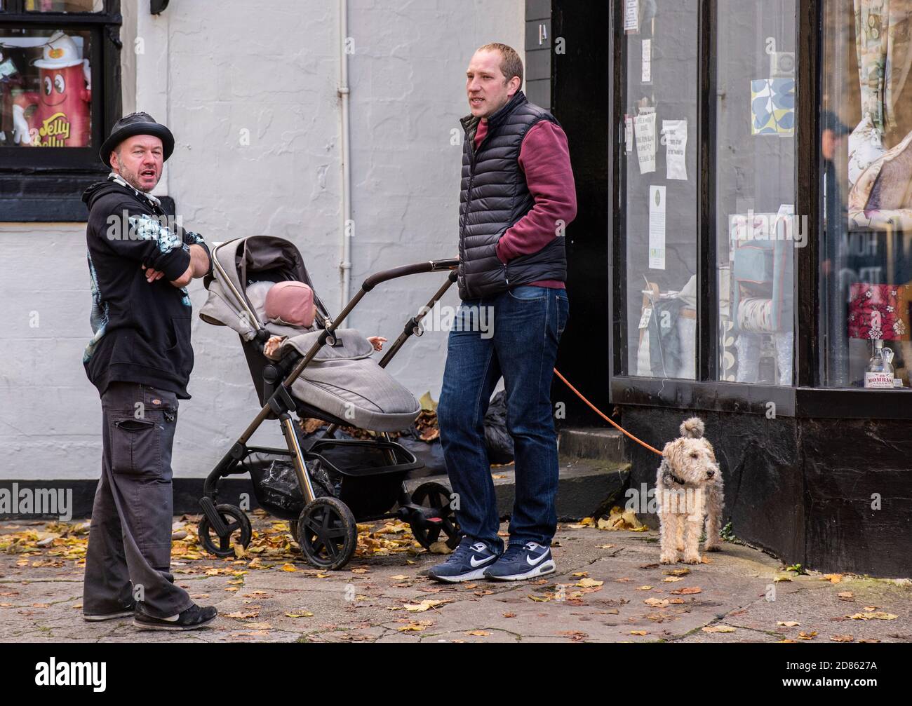 Deux hommes avec poussette et chien par magasin Banque D'Images