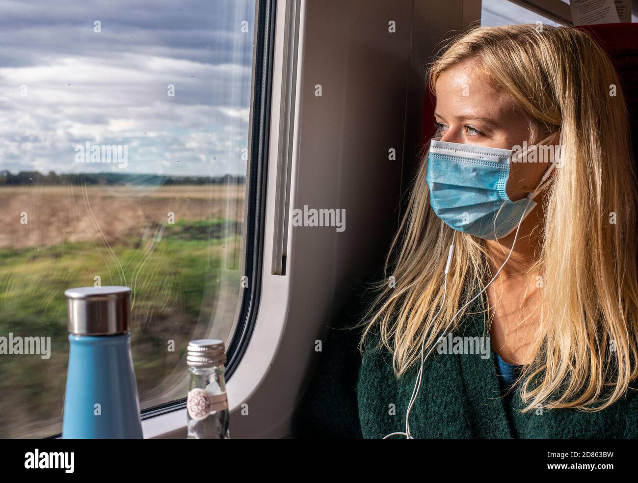 Femme portant un masque sur le train regardant à travers la fenêtre Banque D'Images Femme portant un masque sur le train regardant à travers la fenêtre Banque D'Images