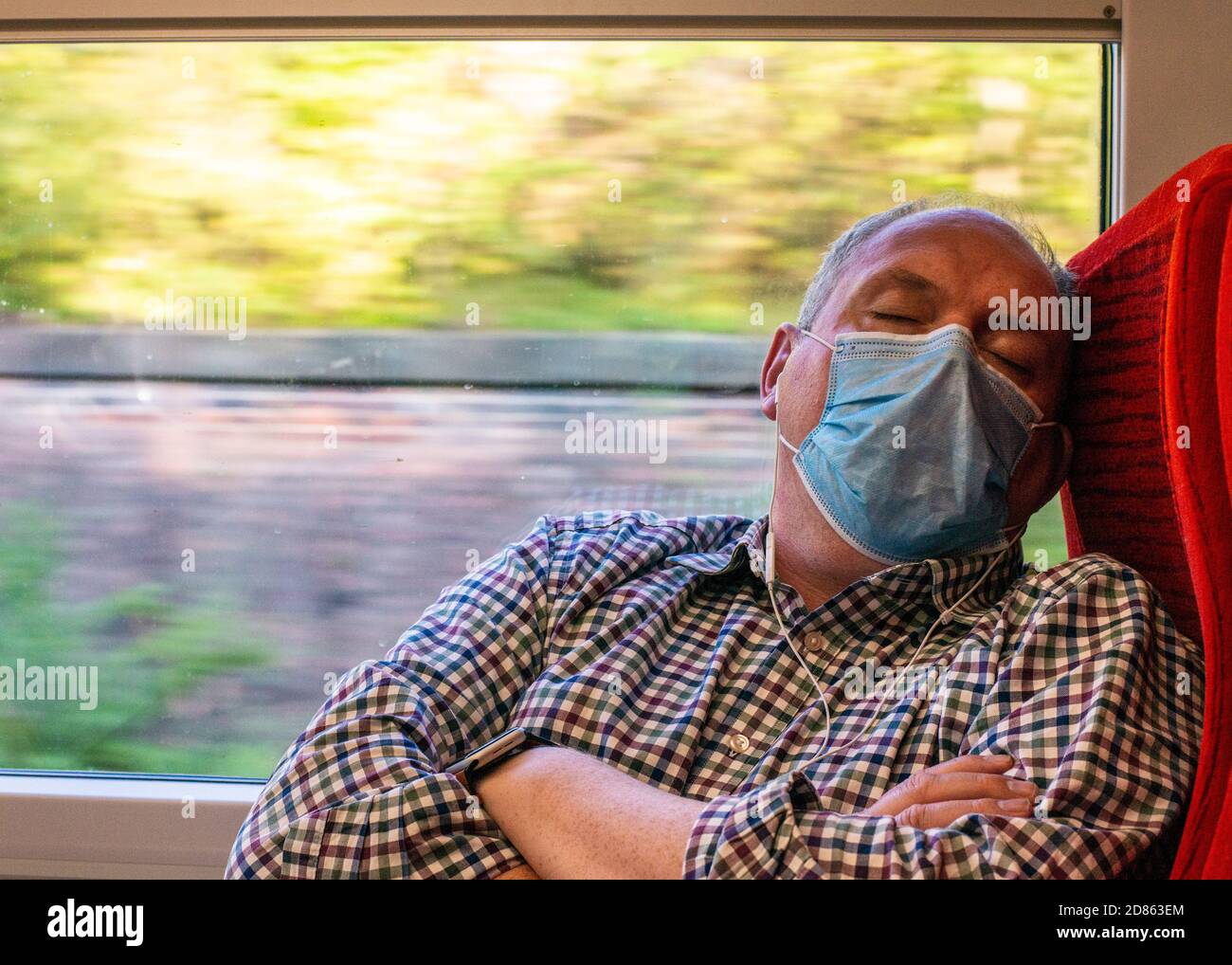 Homme portant un masque facial dormant dans le train Banque D'Images