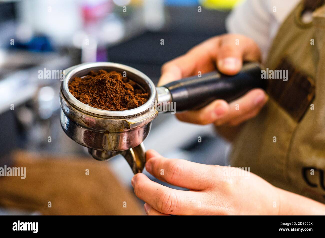 Gros plan sur le barista féminin tenant le café moulu pour préparer l'espresso, le service et le concept de préparation. Banque D'Images