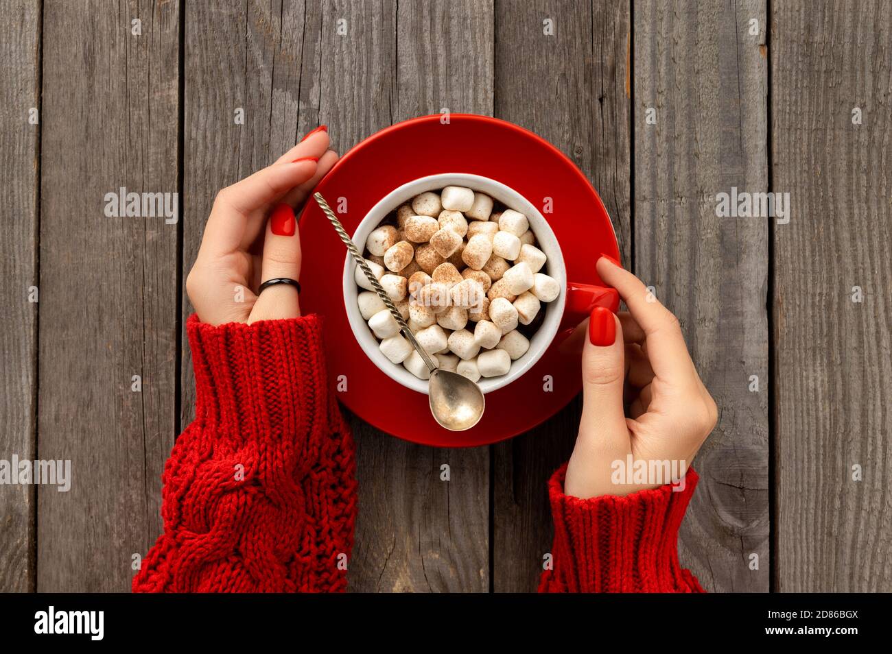 Les femmes tiennent le chocolat chaud avec le guimauve dans une tasse rouge Banque D'Images