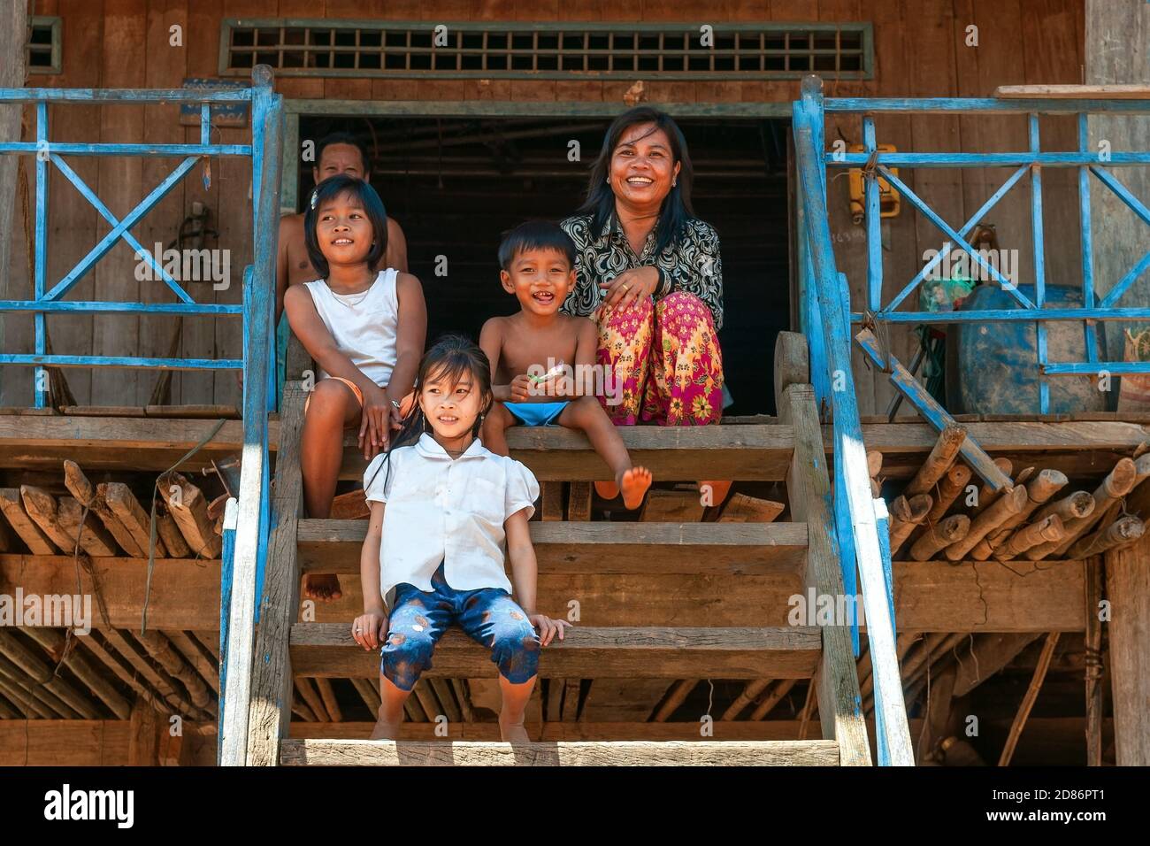 Portrait d'une famille cambodgienne sur l'escalier de leur maison sur pilotis. Banque D'Images