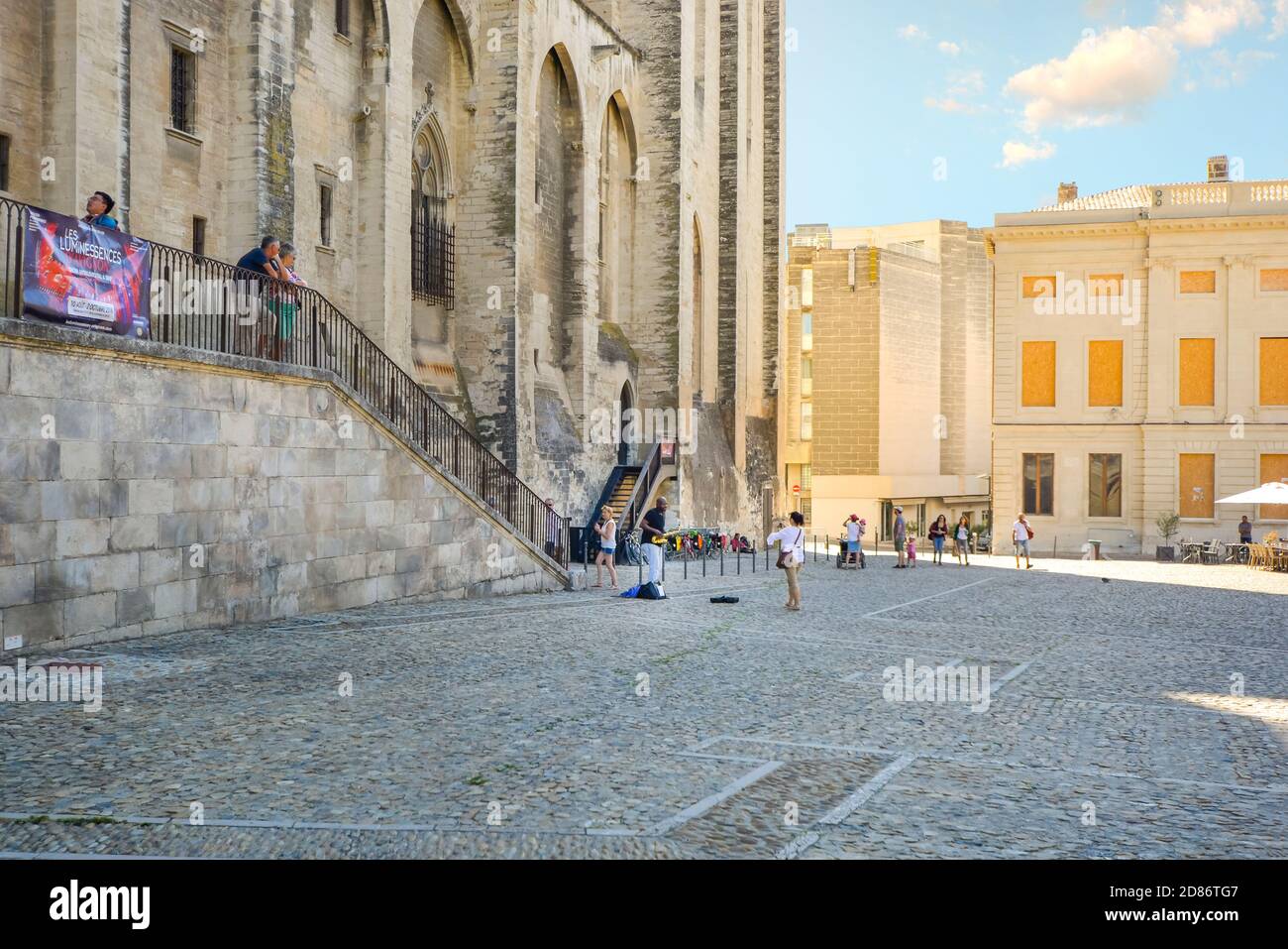 Une touriste prend une photo qu'elle aime un artiste de rue à jouer du saxophone en face de du palais des Papes à Avignon France Banque D'Images