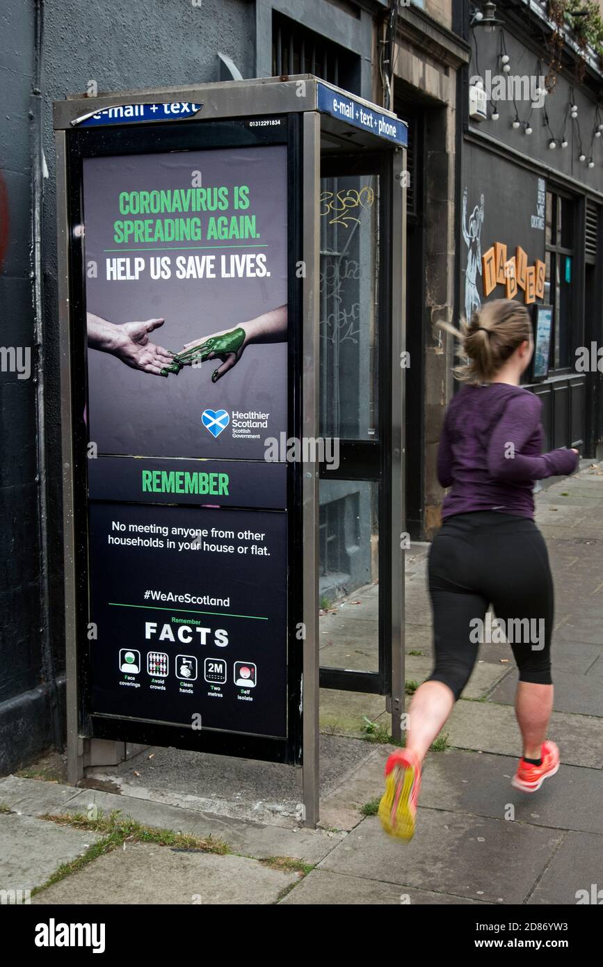 Une jeune femme s'élance devant un téléphone avec une affiche d'information sur LES FAITS. Édimbourg, Écosse, Royaume-Uni. Banque D'Images