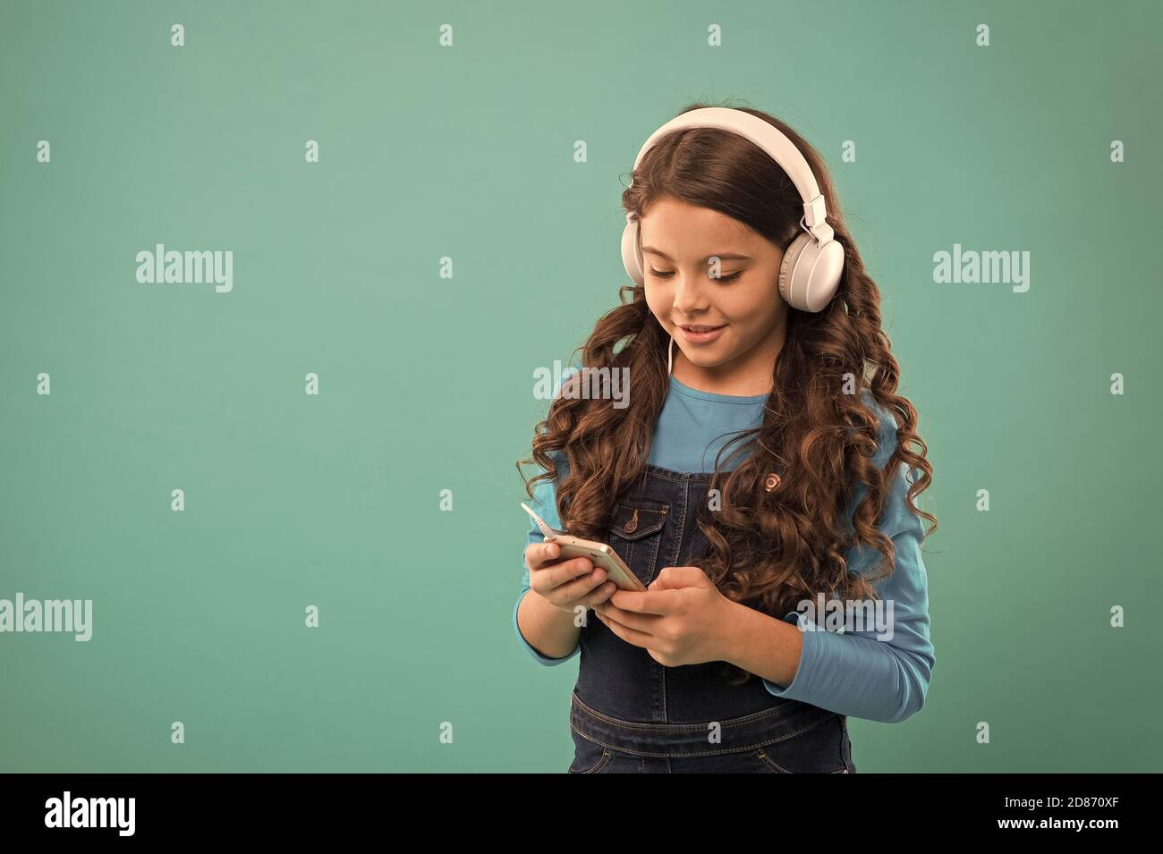 petit enfant faire une liste de jeux sur smartphone. petite fille tient lecteur  mp3. choisir la chanson préférée. e-learning dans la vie moderne. écolière  utiliser la nouvelle technologie. gamin écouter de la