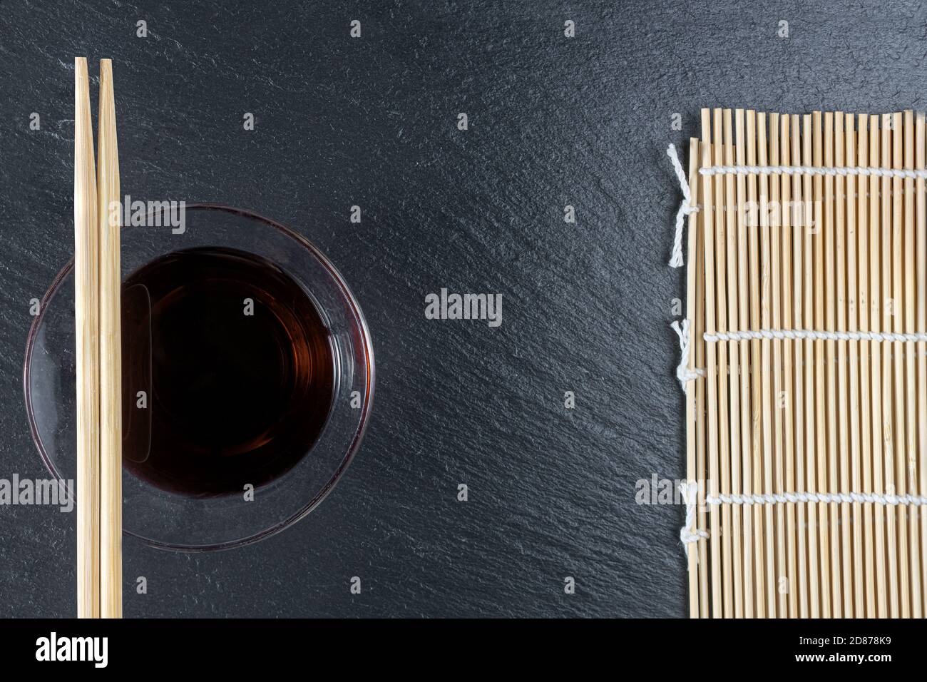 Baguettes, tapis à sushis et sauce soja dans un bol. Mise en page à plat. Espace pour le texte Banque D'Images