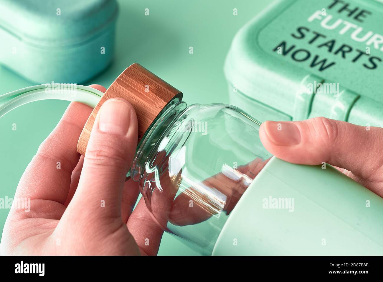 Bouteille de verre réutilisable dans les mains des femmes. Boîtes à lunch biodégradables. Un style de vie sans gaspillage, une consommation consciente. Banque D'Images