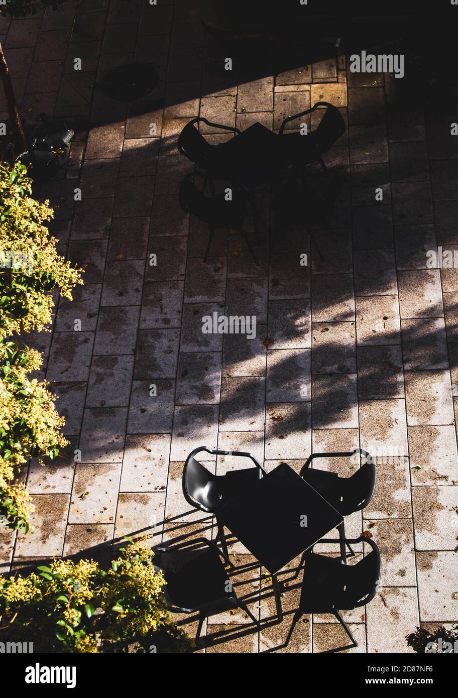 table et chaises sur la terrasse d'un bar avec soleil et ombre Banque D'Images