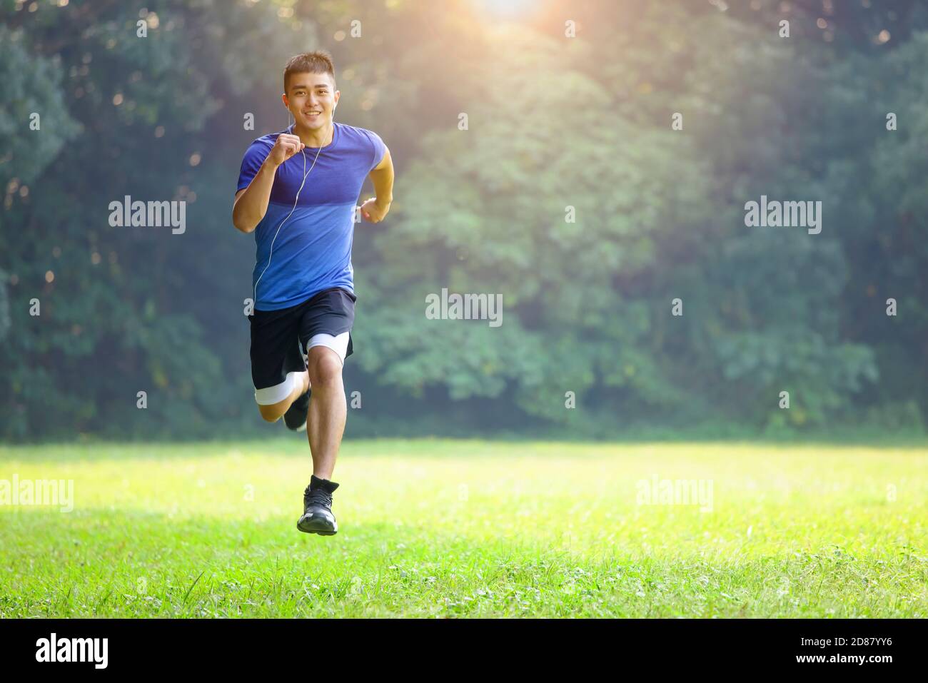 Jeune homme en forme physique et courant dans le parc le matin Banque D'Images