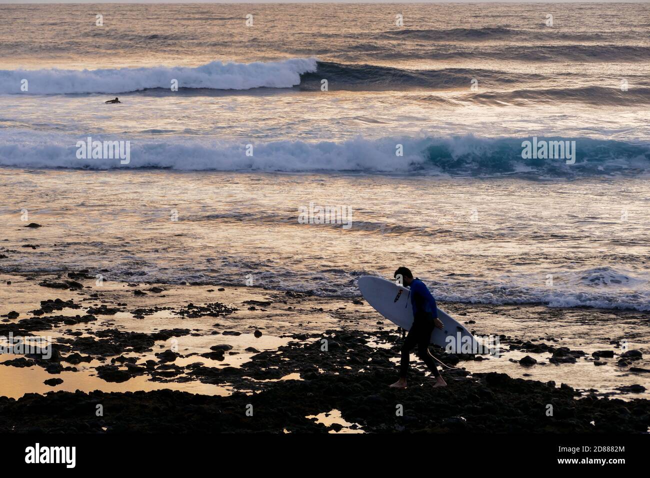 Surfer au coucher du soleil sur une mer calme Banque D'Images