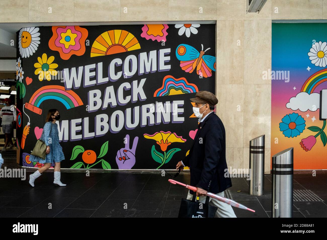Melbourne, Australie. 28 octobre 2020. Les personnes portant des masques de visage marchent à côté des fenêtres David Jones « Welcome Back Melbourne » au centre commercial de Bourke Street lors de la réouverture.la ville de Melbourne regorge de gens qui font du shopping et qui apprécient la première journée de restrictions assouplies, où les magasins, les pubs et les restaurants sont rouverts. Crédit : SOPA Images Limited/Alamy Live News Banque D'Images