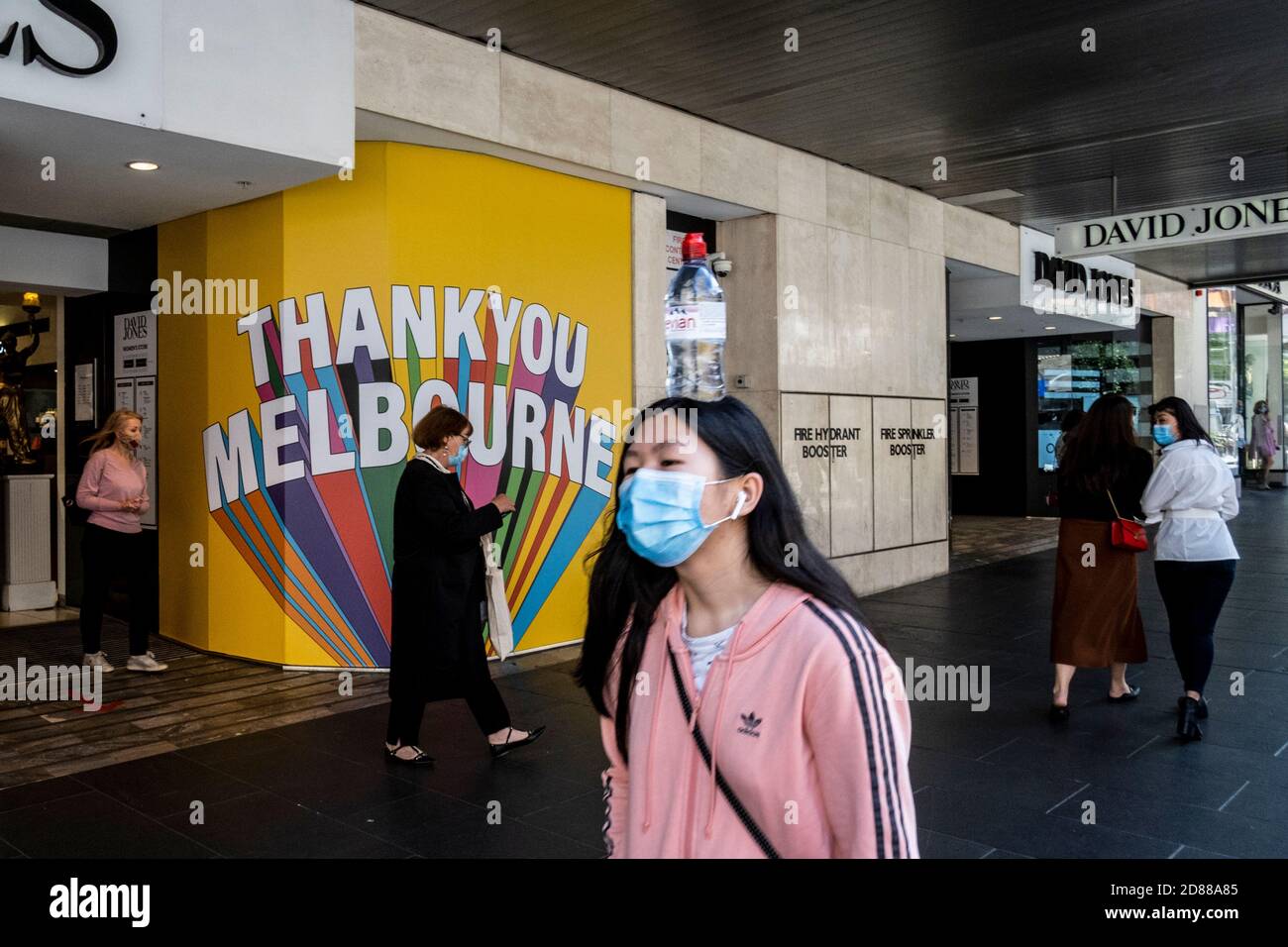 Melbourne, Australie. 28 octobre 2020. Une femme portant un masque facial se promène à côté des fenêtres de David Jones « Merci Melbourne » au centre commercial de Bourke Street lors de la réouverture.Melbourne regorge de gens qui font du shopping et qui apprécient la première journée de restrictions assouplies, où les magasins, les pubs et les restaurants sont rouverts. Crédit : SOPA Images Limited/Alamy Live News Banque D'Images