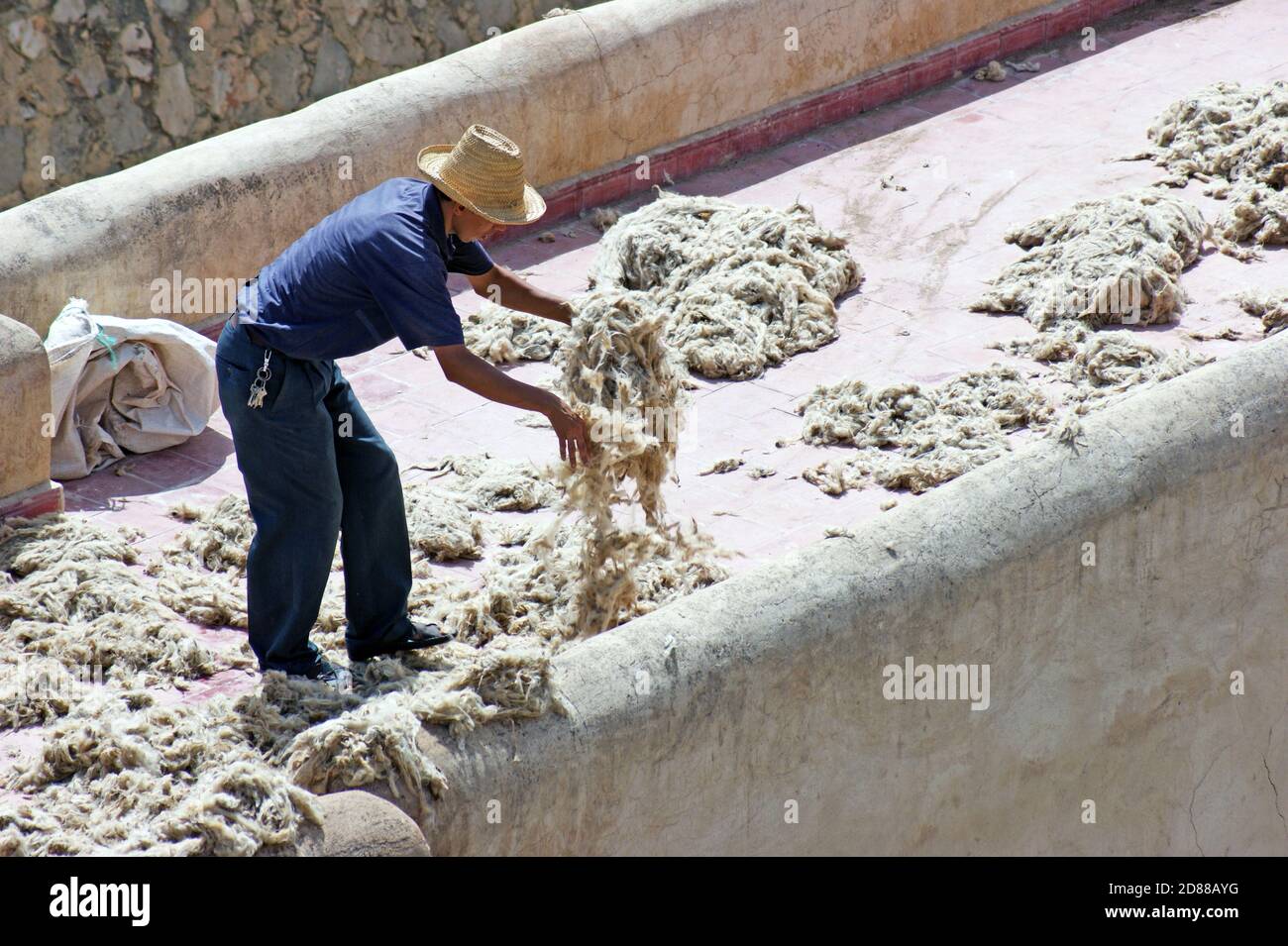 Un ouvrier de tannerie de Chouara recueille les cheveux dans le cadre du processus de production du cuir dans la vieille médina de Fès, au Maroc, en Afrique. Banque D'Images