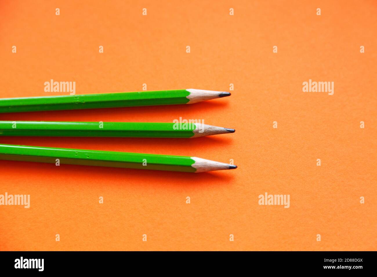 trois crayons verts sur fond orange Banque D'Images