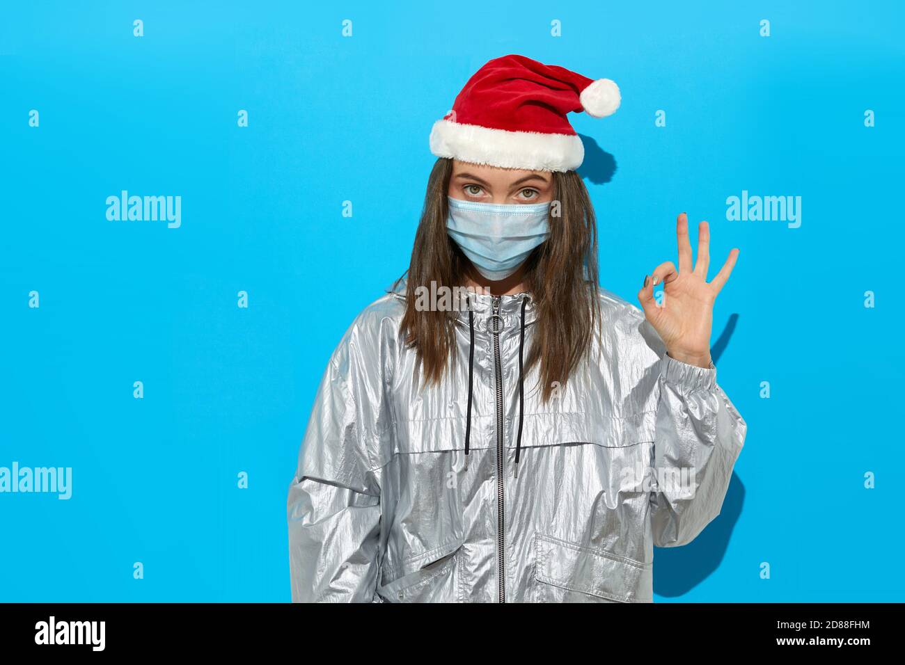 Femme en chapeau de père Noël et masque médical en studio Banque D'Images Femme en chapeau de père Noël et masque médical en studio Banque D'Images