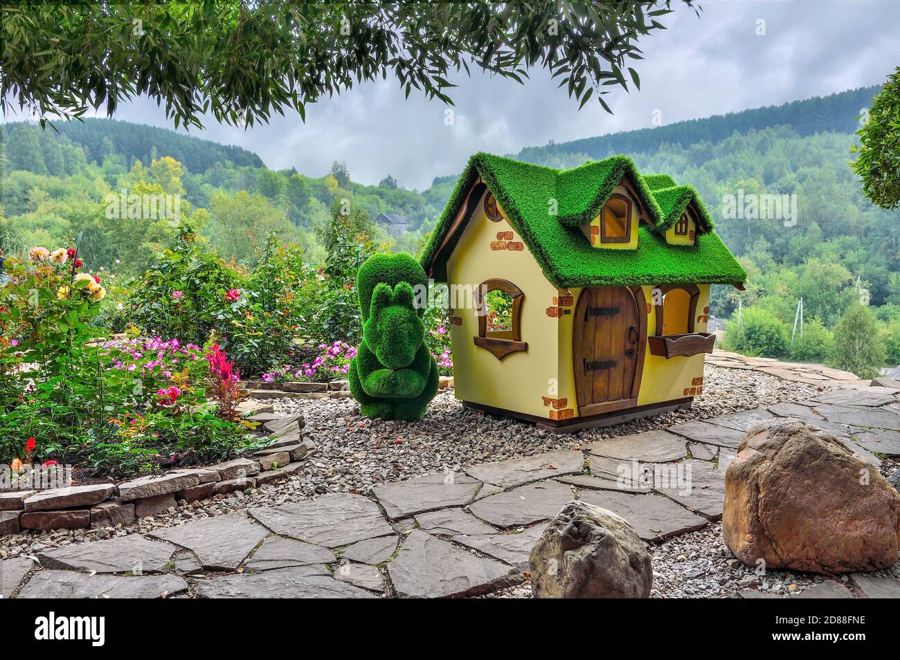 Novokuznetsk, Russie - 15 août 2020 : sculpture verte d'écureuil près de la petite maison, créée à partir d'herbe artificielle - jardins topiaires. Jardin de roses - Banque D'Images