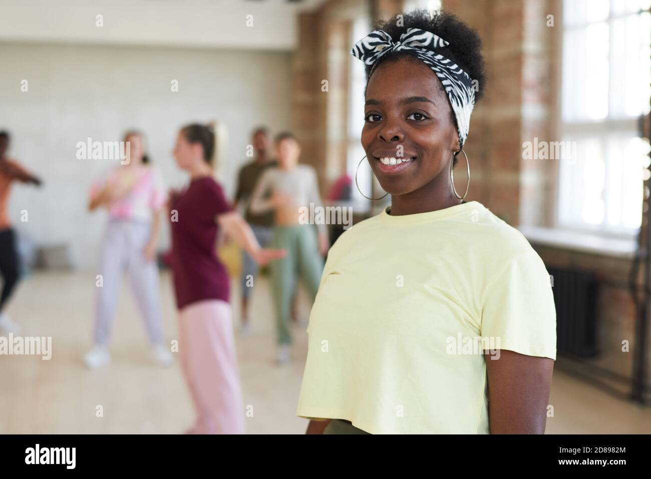 Portrait de la jeune femme africaine souriant à la caméra pendant l'entraînement en studio de danse Banque D'Images
